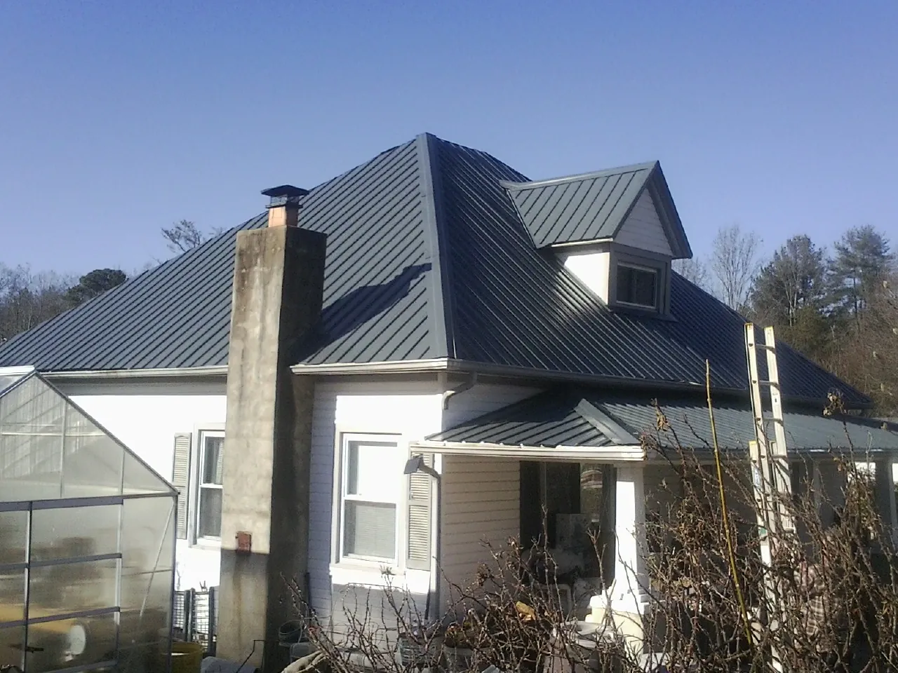 Dark blue standing seam metal roof on a white farmhouse with dormer — Slate & Tile Roof Repair by Roofing Brothers in Robeline