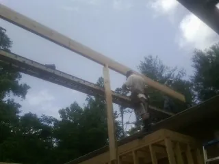 Carpenter setting a ridge beam over a new addition frame — Ice Dam Removal by Roofing Brothers in Robeline