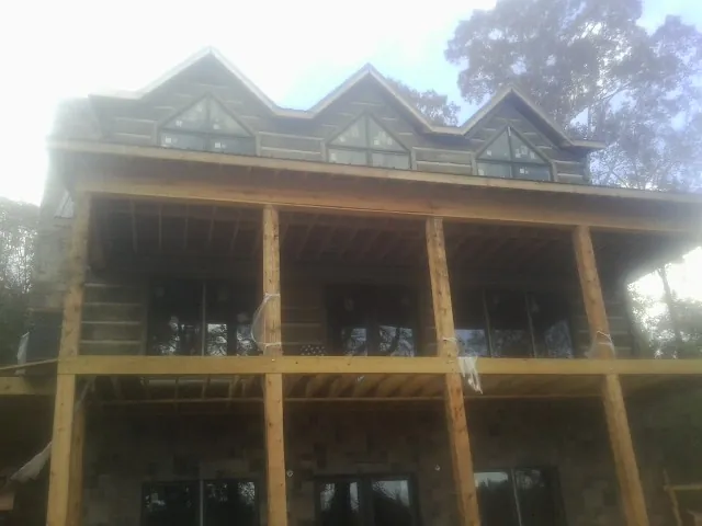 Dormers and porch framing on a large log home under construction — Roof Coating work by our crew in Robeline